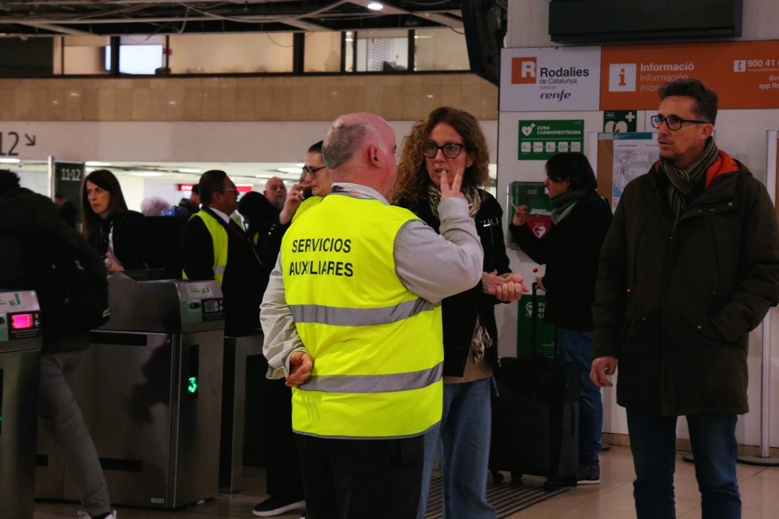 Un informador de Renfe parlant amb usuaris a l'estació de Sants de Barcelona | Andrea Salazar (ACN)