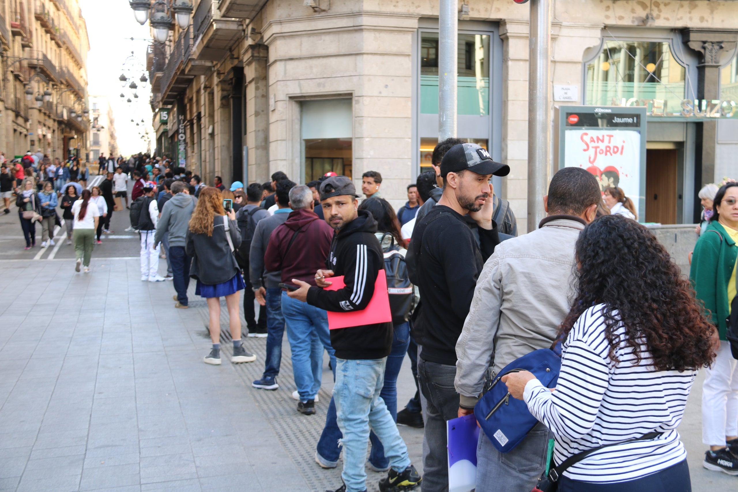 La cua de migrants per fer tràmits per la regularització arriba des de la plaça de Sant Miquel a la Via Laietana. |Miquel Codolar (ACN)