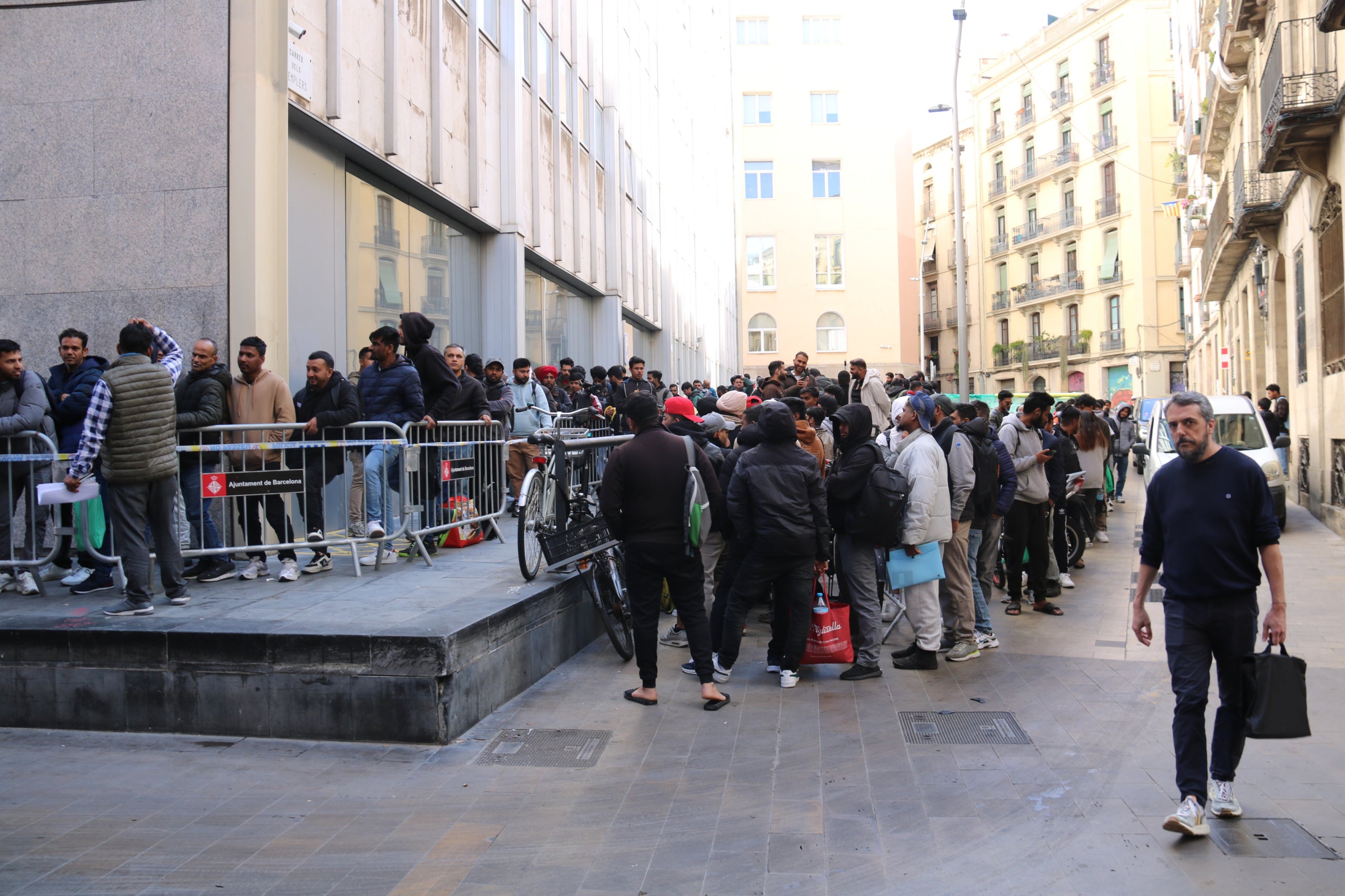 La cua de migrants per fer tràmits per la regularització dona diverses voltes al darrere de l'Ajuntament de Barcelona. | Miquel Codolar (ACN)