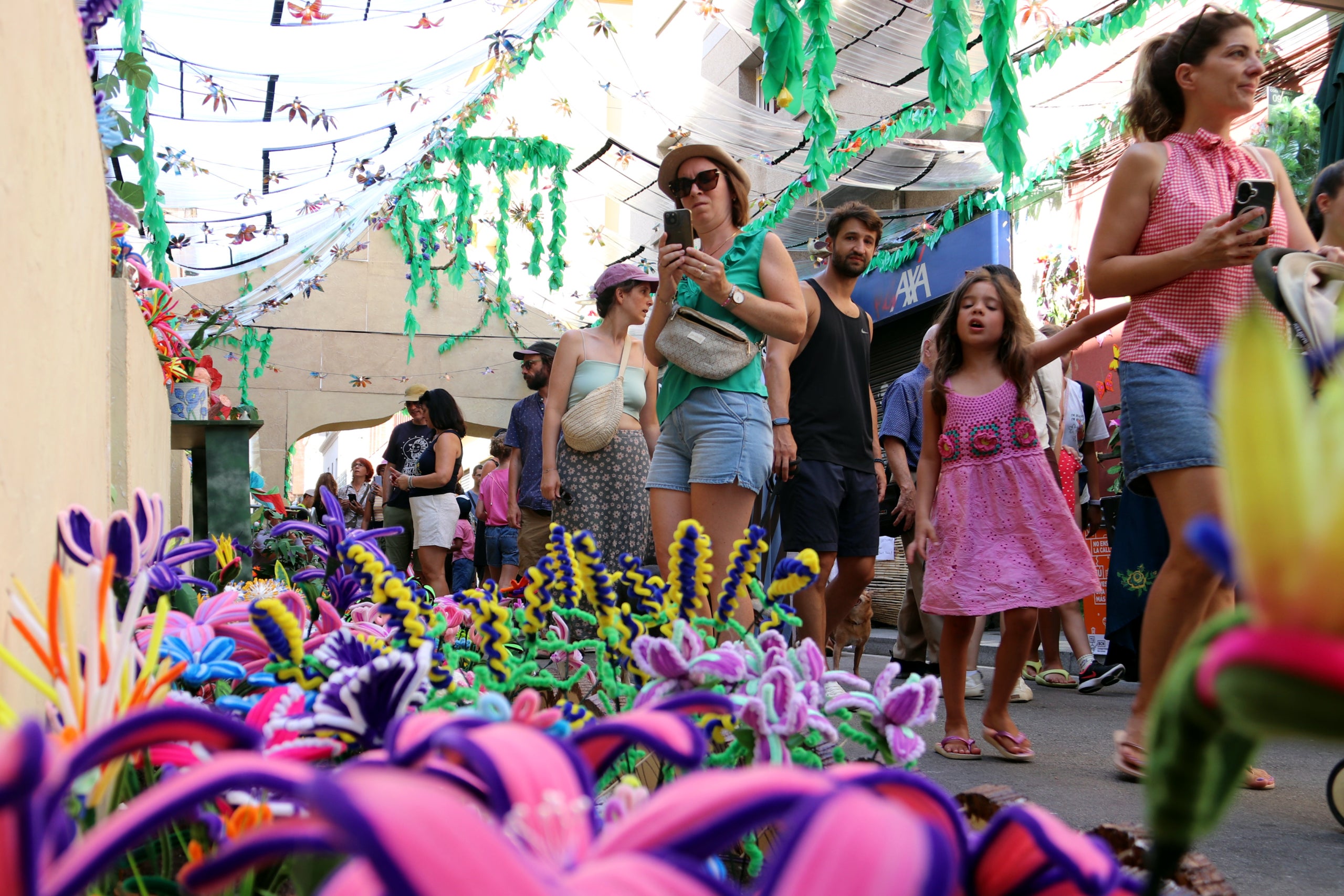 Una dona fotografia un dels carrers guarnits del barri de Gràcia durant la Festa Major Autor: Oriol Escudé Macià