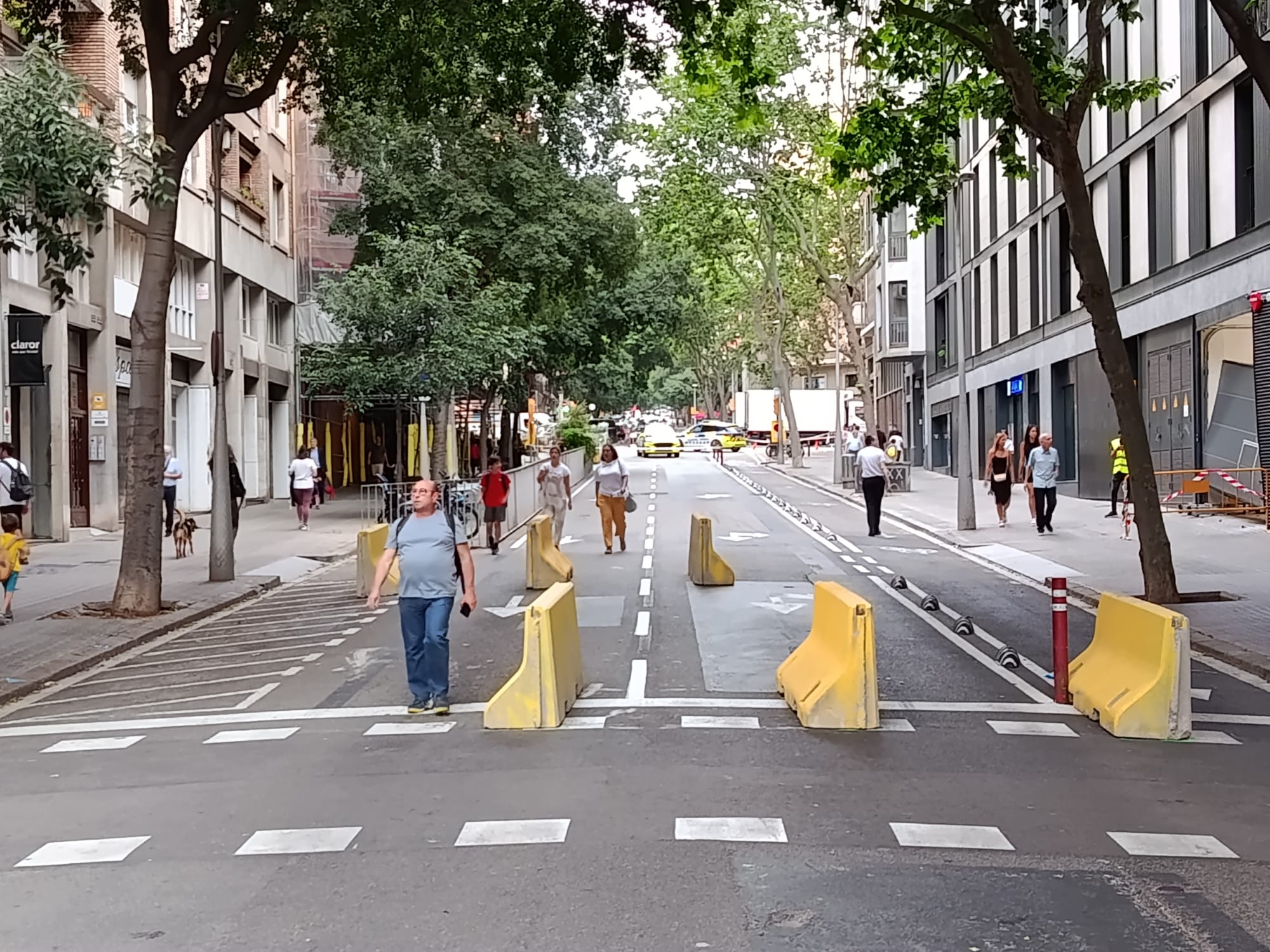 Un carrer tallat, al barri de la Sagrada Família, amb tanques de formigó mentre ciutadans caminen per la calçada / Jordi Subirana