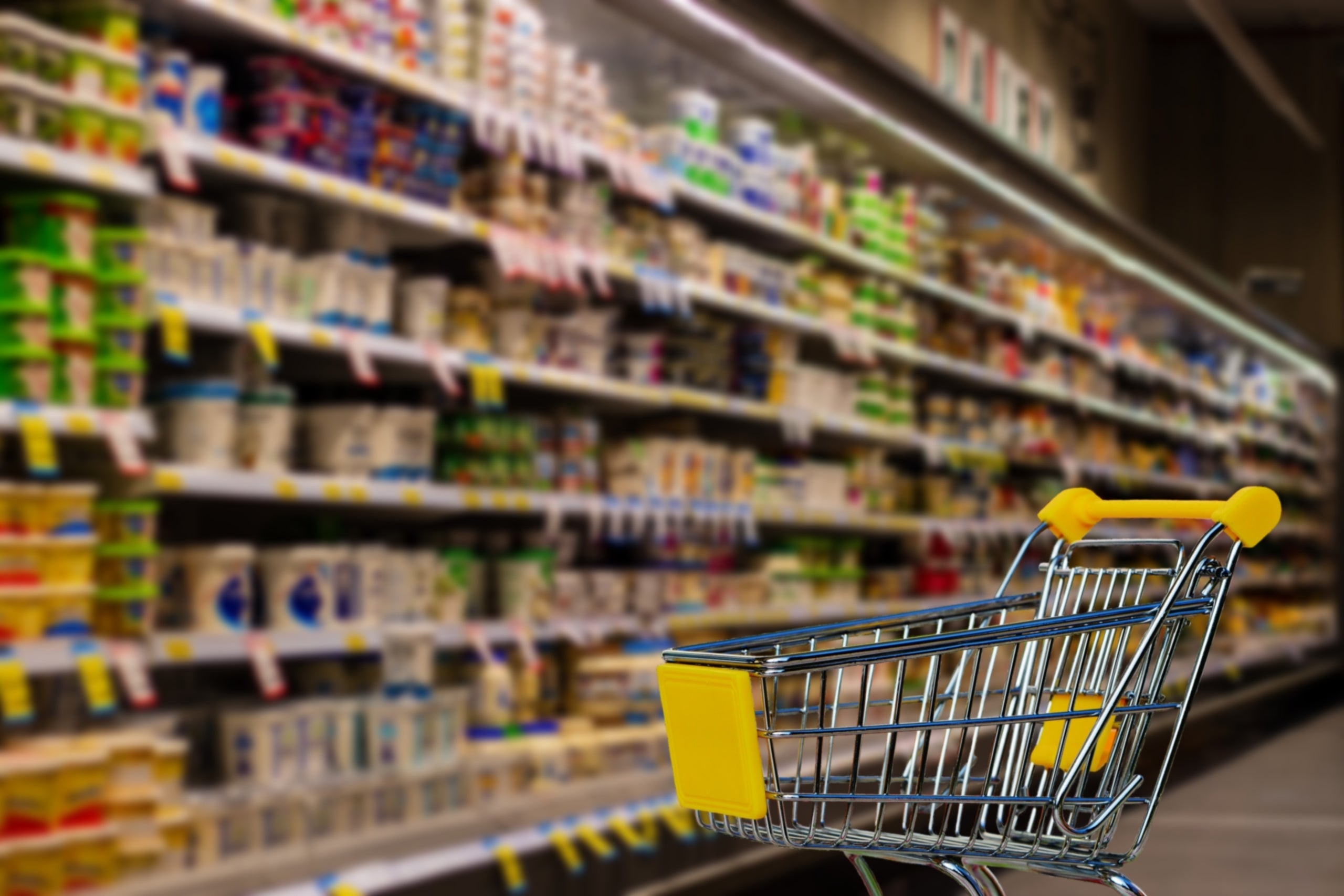Un carretó de supermercat davant d'una estanteria plena de productes / Pixabay