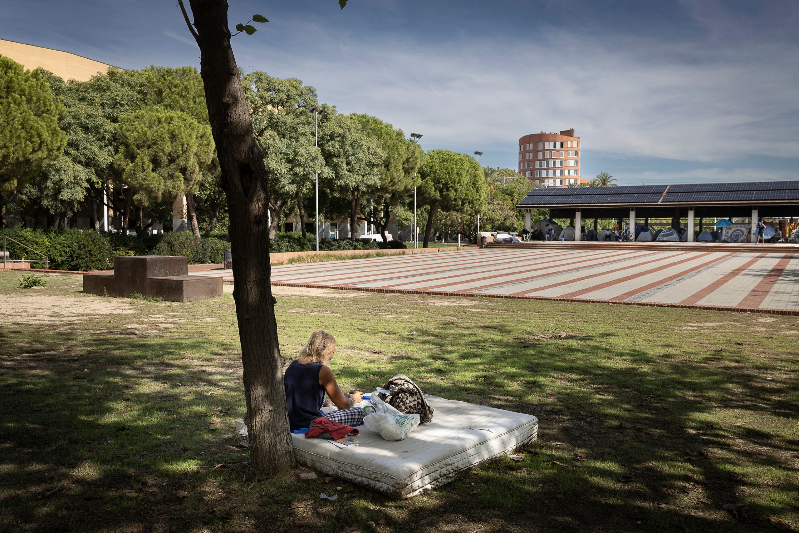 Una persona amb un matalàs, a la plaça dels Campions de la Vila Olímpica, aquest setembre / Jordi Play

